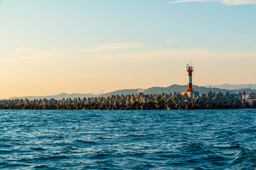 View of the lighthouse on the northern mole of Sochi from the sea at sunset, Russia
