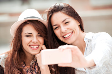 Two young girls smiling using smart phone in a cafe.