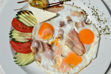 Plate with served decorated breakfast - fried eggs, bacon and fresh vegetables