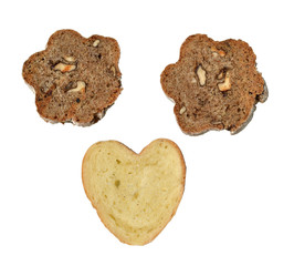 Pieces of domestic, home-made bread with wholegrain and nuts and of white flour, in shape of flower and heart, on white background