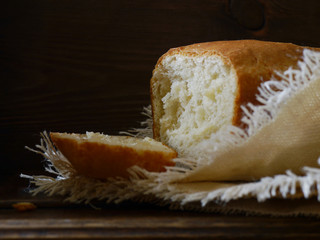 Homemade wheat white bread of rectangular shape on a wooden dark background. Bread on a linen napkin in a rustic style.