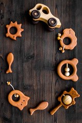 Cute wooden handmade toys for newborn on dark wooden background top view copyspace