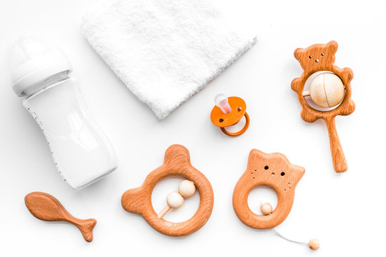 Baby accessories. Wooden toys, pacifier and bottle on white background top view