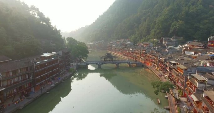 Top view or aerial shot of famous ancient town in Fenghuang County, China. Flying over Green River, hills and houses of the village. Travel,destination and world heritage concept.
