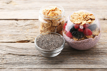 Chia pudding with berries and corn flakes on grey wooden table