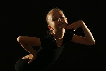 Fototapeta na wymiar Young girl gymnast on black background