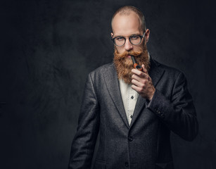 A man smoking pipe over grey background.