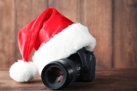 Red santa hat with camera on grey wooden table