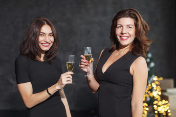 Beautiful girls in evening dresses with glasses of champagne to celebrate the New year