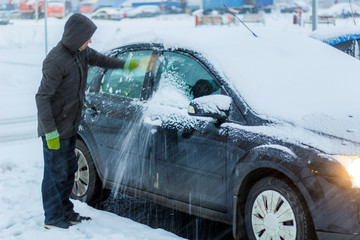man cleans snow from the car.