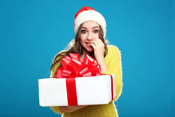Beautiful young girl holding gift box on blue background