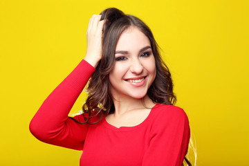 Beautiful young girl in red dress on yellow background