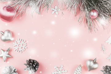 Christmas frame with fir branches, conifer cones, christmas balls and silver ornaments on pastel pink background