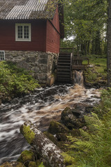 An old water mill located at a river with red waters coloured by iron compounds - obrazy, fototapety, plakaty