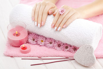 Obraz na płótnie Canvas beautiful pinc manicure with chrysanthemum flower and towel on the white wooden table. spa