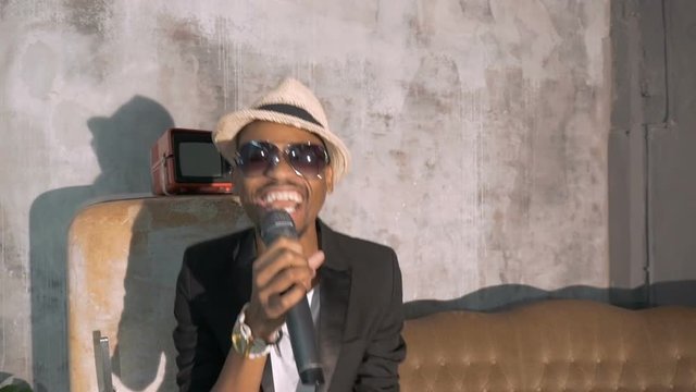 The African man emotionally sings into the microphone.