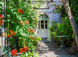 Fototapeta na wymiar Entrance courtyard with flowers and garden furniture