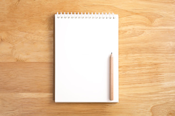 Blank spiral notebook with pencil on wood background