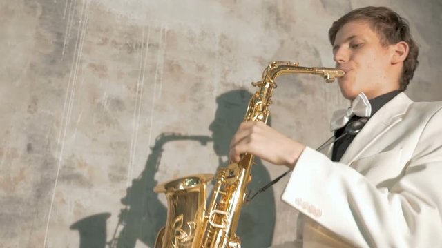 A musician in a white suit plays the saxophone. close-up