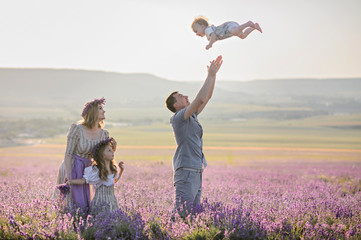 Happy family in a field of lavender on sunset. Girls in amazing dresses walk on the lavender field.