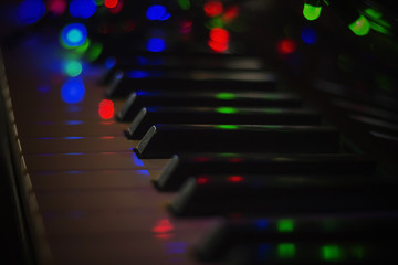 Fototapeta na wymiar Christmas garland with lights on an electronic piano - decoration for the celebration of Christmas and New Year