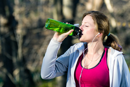 Female runner takes a break from jogging and drinks water