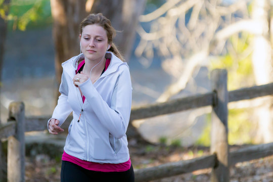Female fitness girl jogging on path in nature landscape outside.