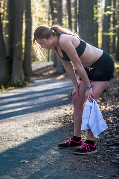 Sporty girl in nature stops to take a rest from jogging.