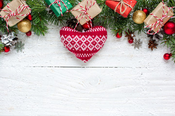 Fototapeta na wymiar Christmas background with fir branches, knitted heart, decorations, gift boxes and pine cones