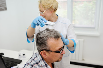 diagnostics hair and scalp. Trihoskopiya. Doctor examine patient male hair a special apparatus