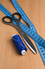 Tools and accessories for sewing. Sewing thread, scissors, tailor tape on a wooden table