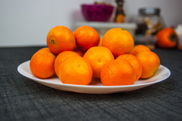 Fresh mandarin oranges stacked on a white plate