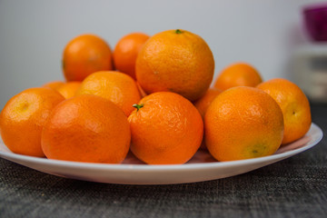 Fresh mandarin oranges stacked on a white plate