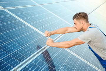 Young worker installing solar panels outdoors