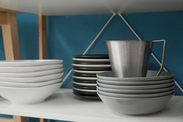 Storage stand with dishware and metal pitcher near color wall
