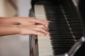 Little girl playing piano indoors, closeup