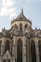 Apse on the east end of St Peter's Church (Sint Peterskerk) in Leuven, Belgium.  Close up of apse with buttresses and tracery of Saint Peter's Church in Leuven, blue sky and clouds.