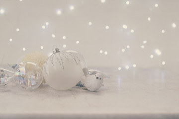 White winter christmas scene with glass ball and bird decorations with copy space, christmas bokeh lights in background, retro toned