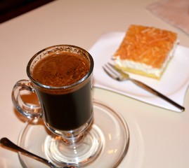 Black coffee on a glass cup on a wooden table.