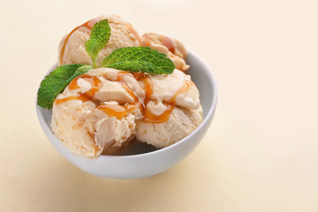 Bowl with caramel ice cream on light background