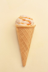 Waffle cone with caramel ice cream on light background