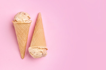 Waffle cones with caramel ice cream on color background