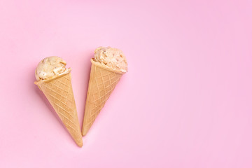Waffle cones with caramel ice cream on color background