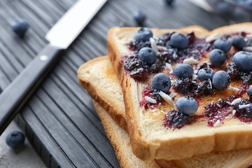 Tasty toasts with jam and blueberries on board, closeup