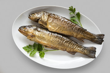 Geräucherte Forellen auf einem Porzellanteller.