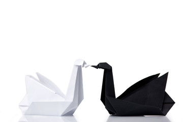 White and black swans. Beautiful paper figurines, result of origami or folding instructions. Art and creativity.