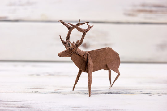 Deer figurine on wooden background. Beautiful handmade art, origami or paper folding. Crafts and creative skills.