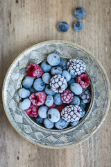  frozen berries in a metal plate on a wooden background