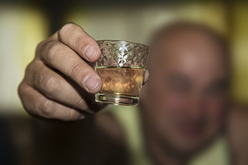 the glass of whiskey in the man's hand on blurred background, close up