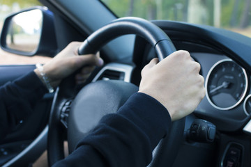 driver's hands grabbing the steering wheel of the car